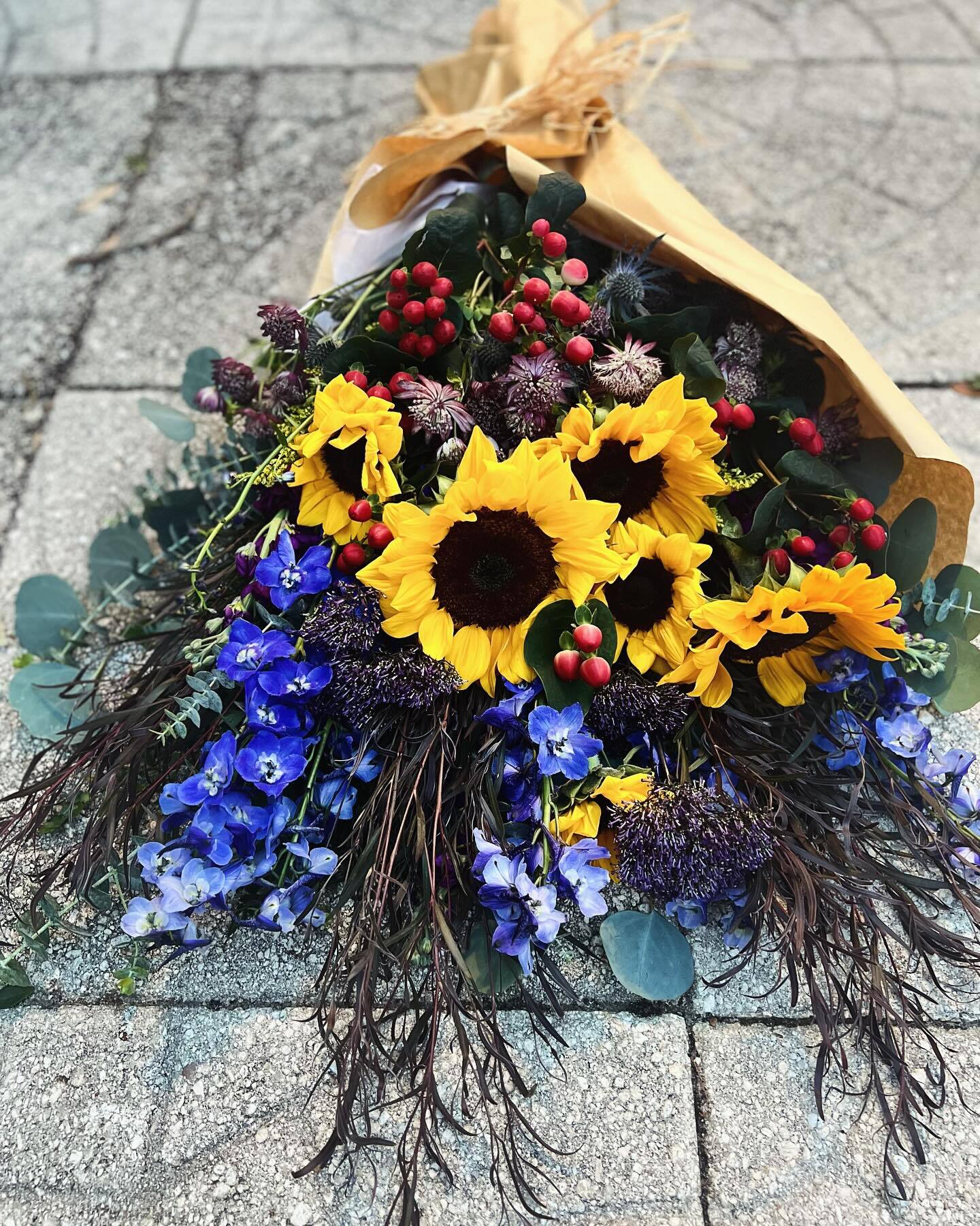 Wrapped bouquet of sunflowers and blue delphinium